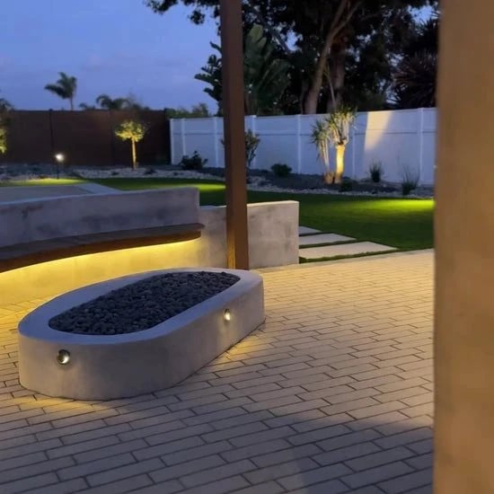 Lit fire feature and seat wall on a patio at night