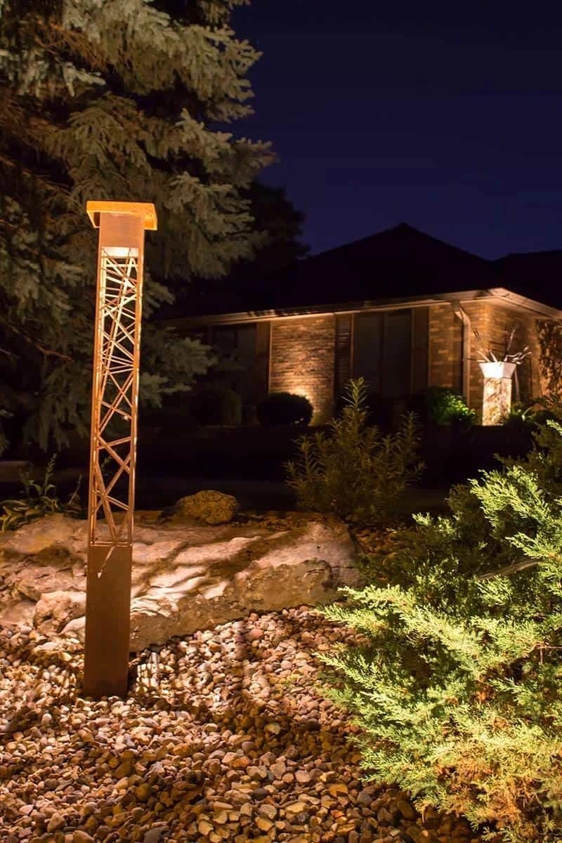 Curved concrete seat wall with LED strip lighting on a paver patio at night
