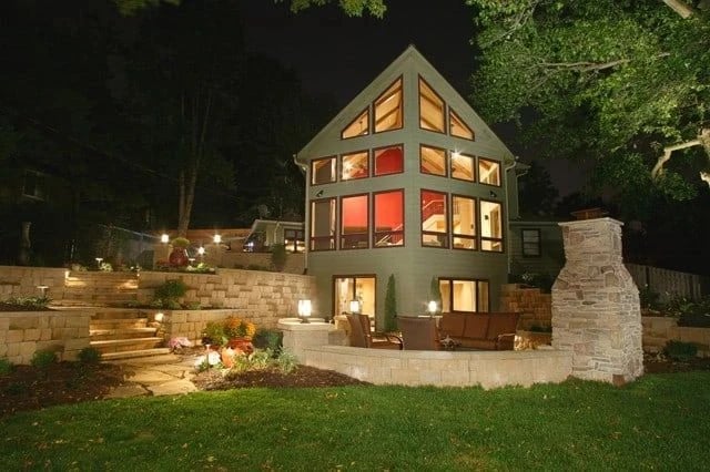 Mountain home with warm uplighting and a stone patio