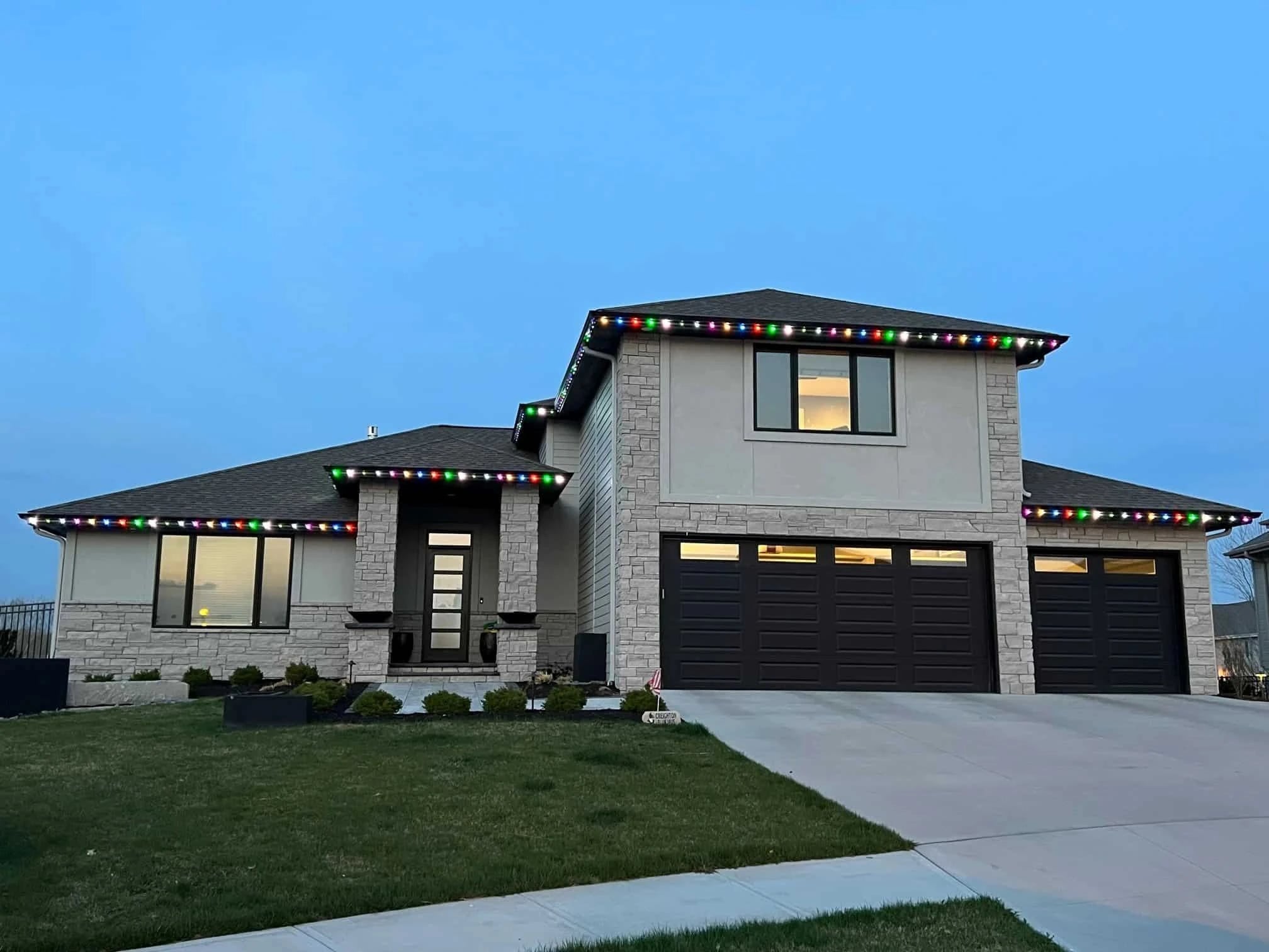 Modern stucco home with multicolor roofline lighting at dusk